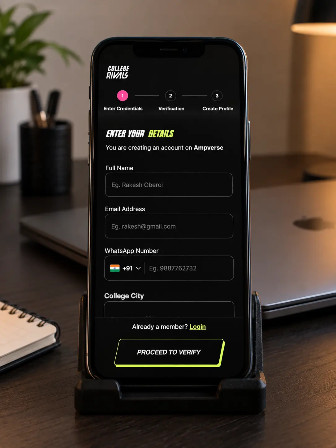 A phone on a stand on a dark desk showing the College Rivals sign-up page: Enter your details, with fields for name, email and WhatsApp number