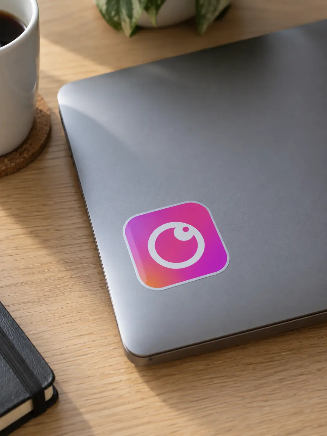 The concept app icon as a vinyl sticker on a grey laptop lid on an oak desk