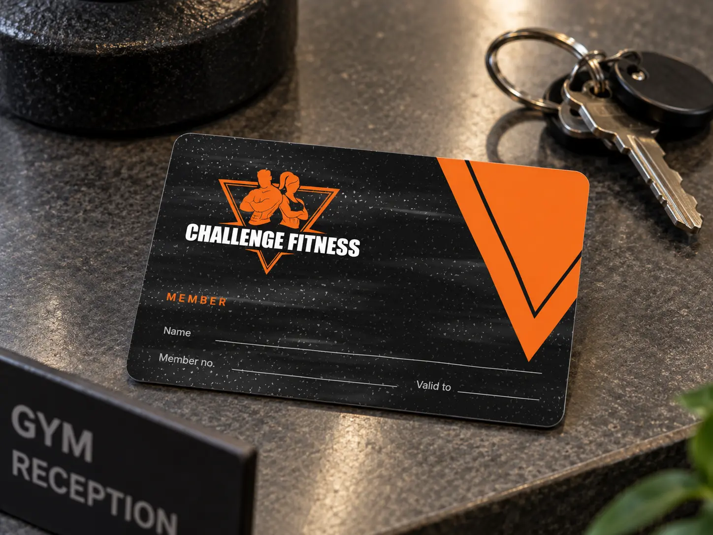 A black Challenge Fitness membership card on a reception counter beside a key ring