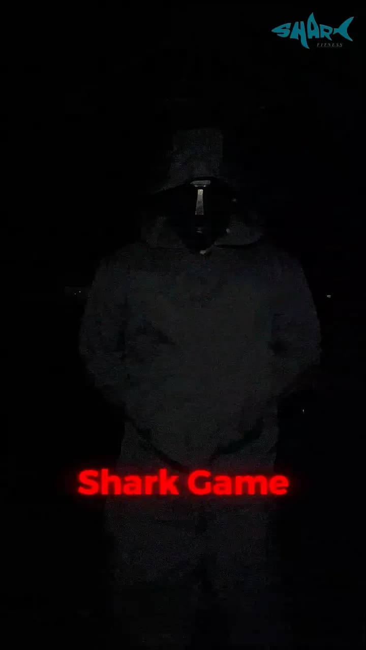 A hooded figure standing in a dark gym, lit green