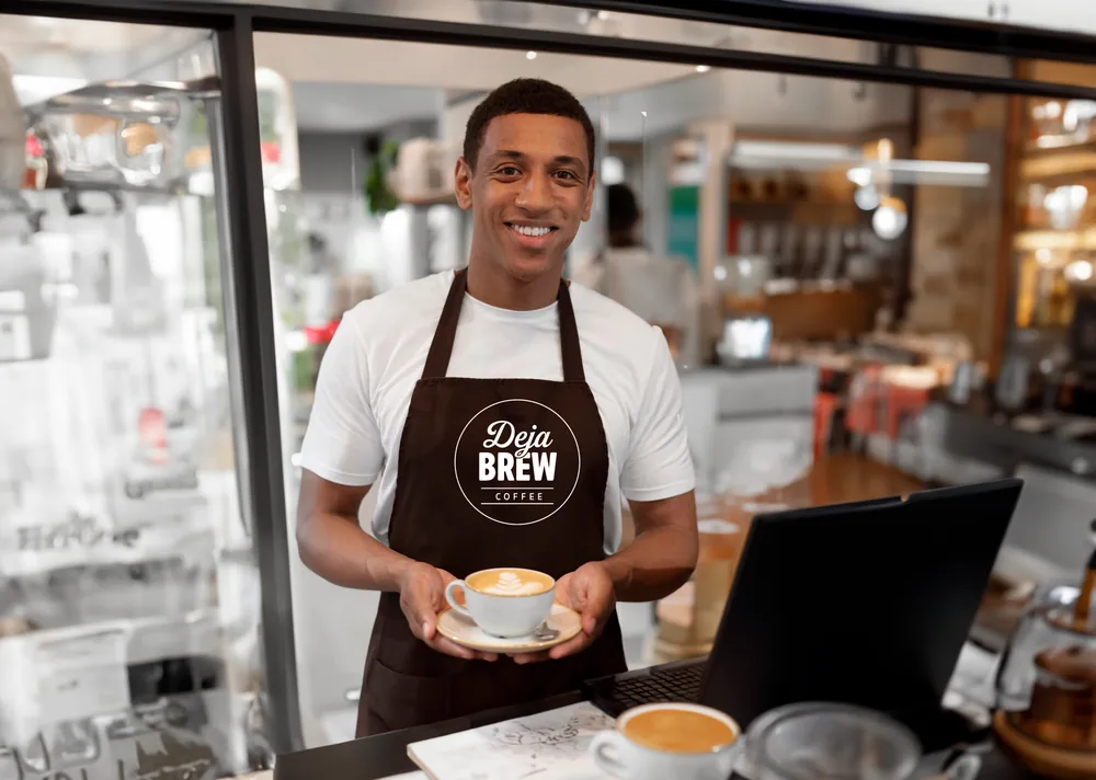 A barista in a Deja Brew apron holding out a cappuccino.