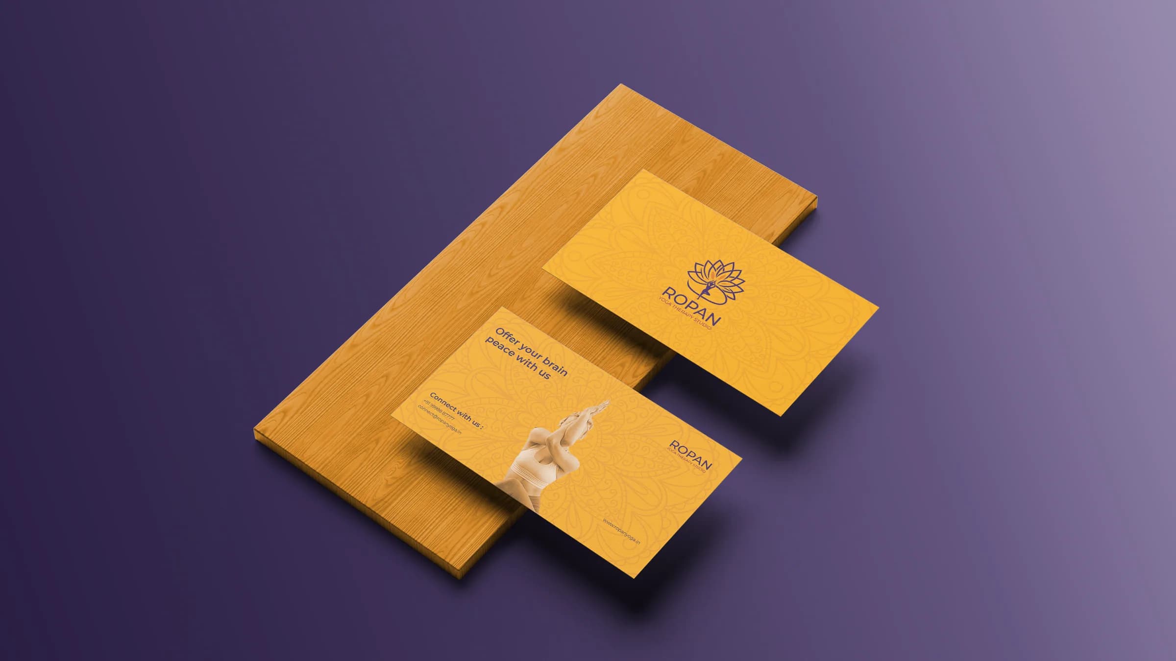 Two amber Ropan visiting cards with the mandala pattern on a wooden block, against a purple ground.