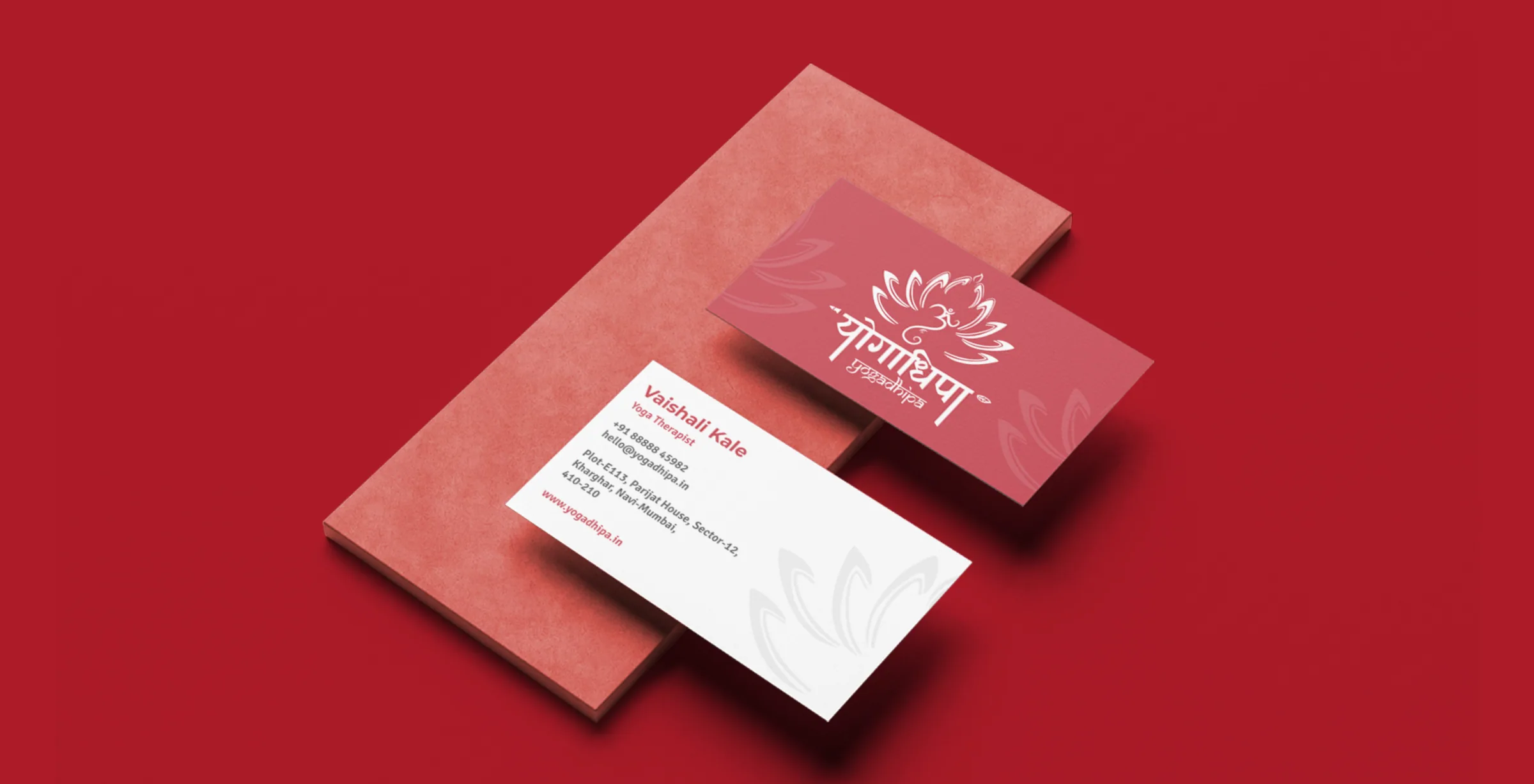 Yogadhipa visiting cards on a crimson ground: a red card with the white lotus logo and a white card with the therapist's details.